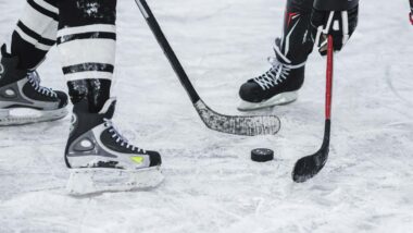 Close up of hockey players with a hockey puck, representing the NHL class action lawsuit.