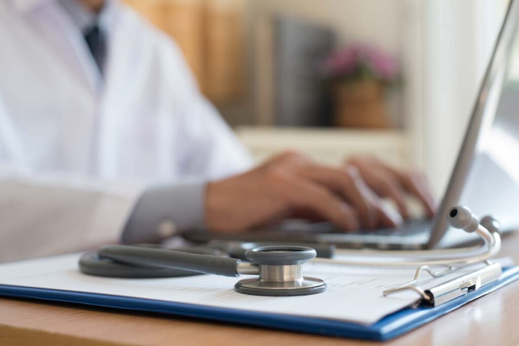 Close up of a doctor typing on a laptop, representing the MyEggBank and Reproductive Biology Associates data breach class action settlement.