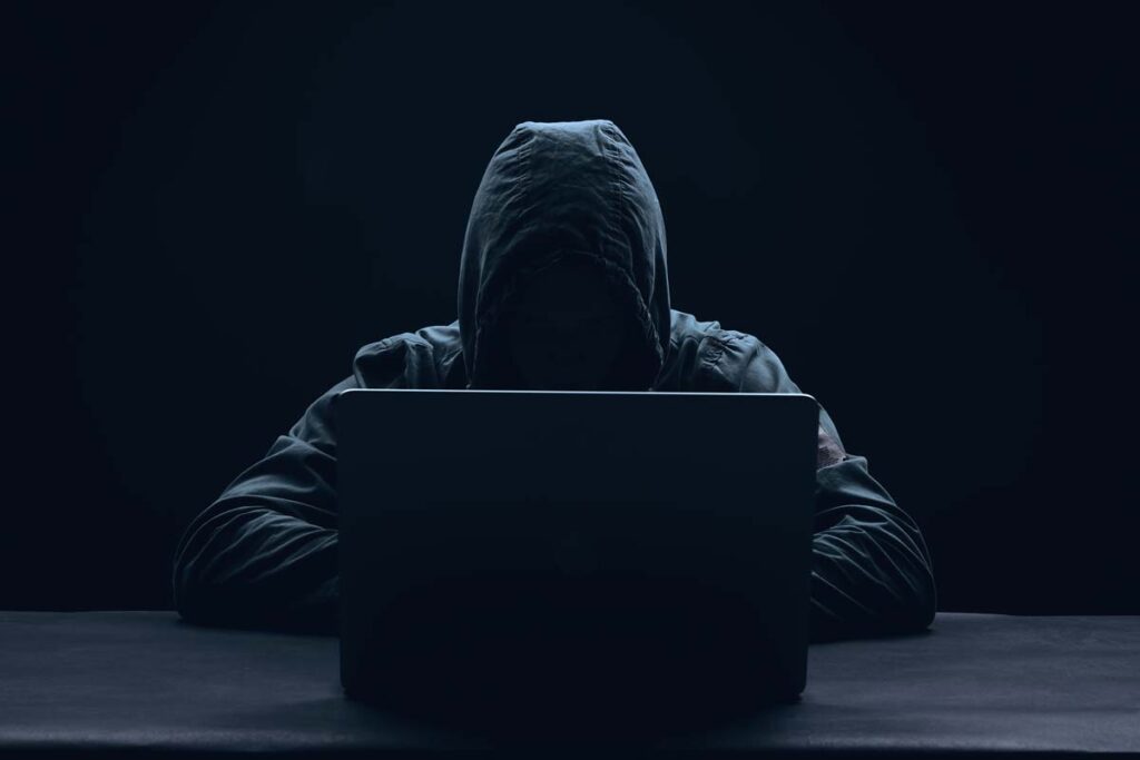 A hooded hacker using a laptop, representing the Integris Health class action.