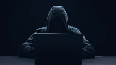 A hooded hacker using a laptop, representing the Integris Health class action.