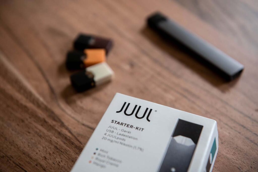 Close up of Juul starter kit on a wood table, representing the Altria e-cigarettes settlement.