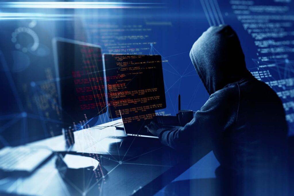 A hooded hacker using a computer, representing the Sovos Compliance data breach settlement.
