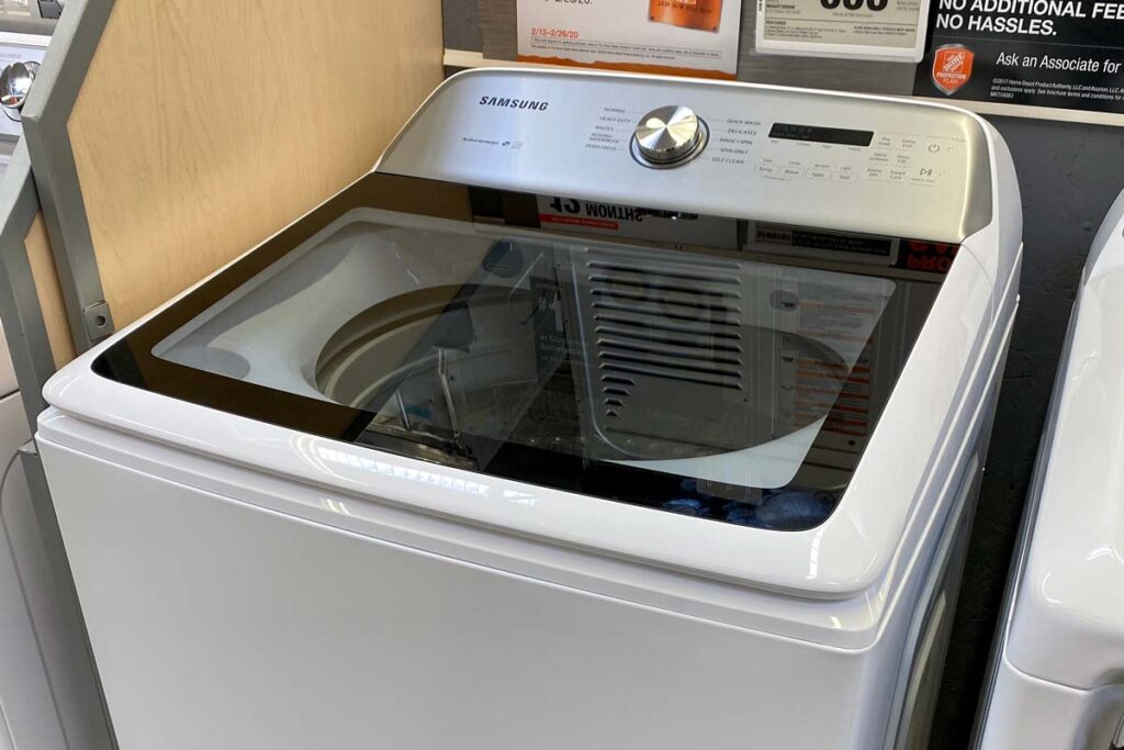 Closeup of a Samsung top-loading washing machine on display at a store, representing a class action over claims the machines can corrode.