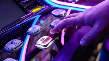 Close up of a males hands pushing a button on a slot machine, representing the Crystal Bay Casino data breach settlement.