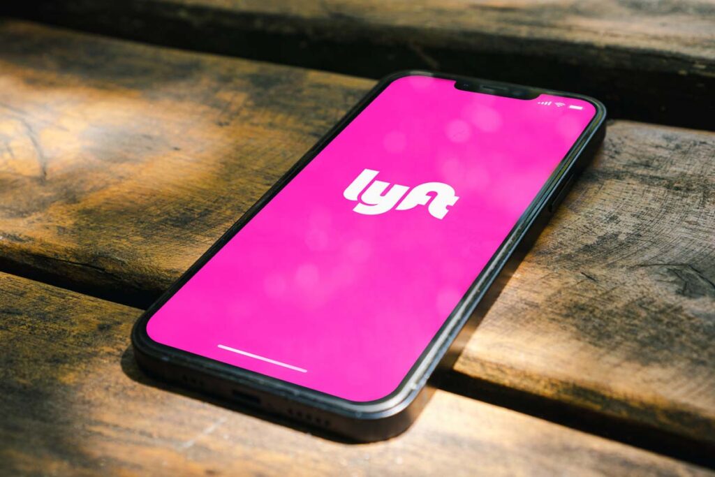 Close up of Lyft logo displayed on a smartphone screen, representing the New York Lyft drivers attorney general settlement. The settlement benefits Lyft drivers who used the Lyft Driver app to provide rides in New York between Oct. 11, 2015, and July 31, 2017, and who had deductions taken for New York sales tax and Black Car Fund fees.