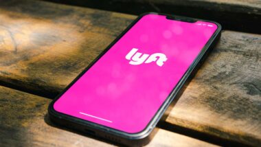 Close up of Lyft logo displayed on a smartphone screen, representing the New York Lyft drivers attorney general settlement.