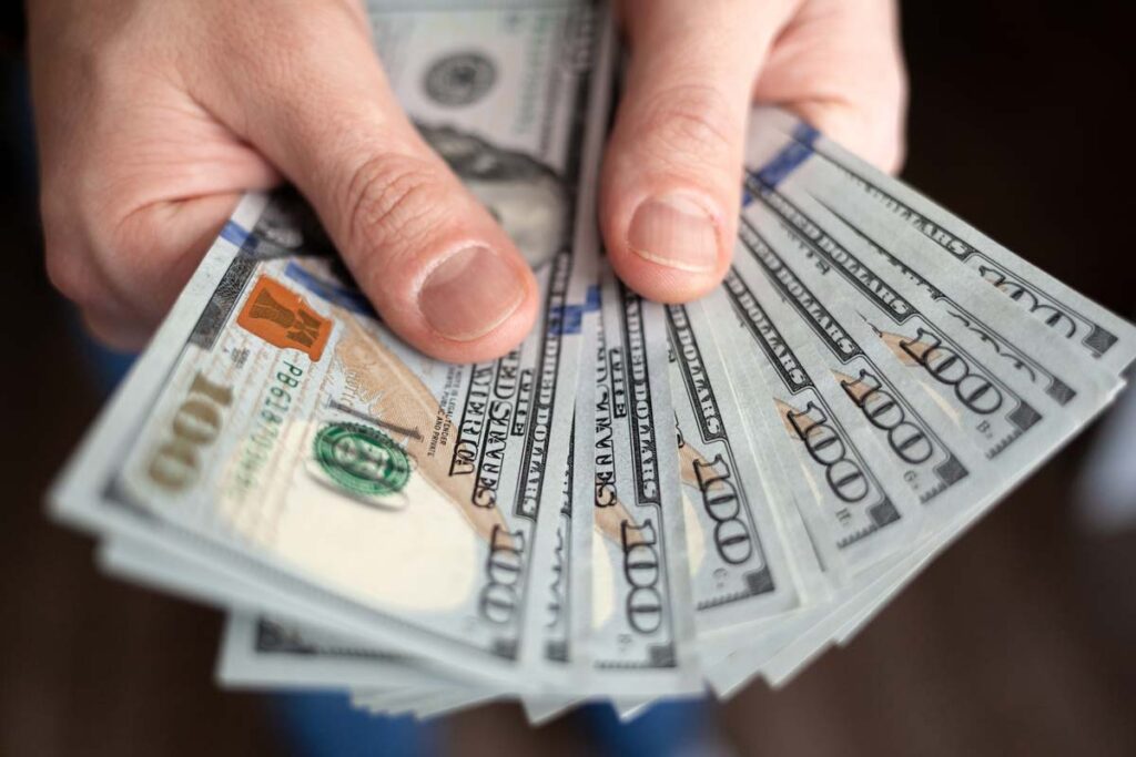 Close up of a mans hands holding cash, representing recent FTC refunds.