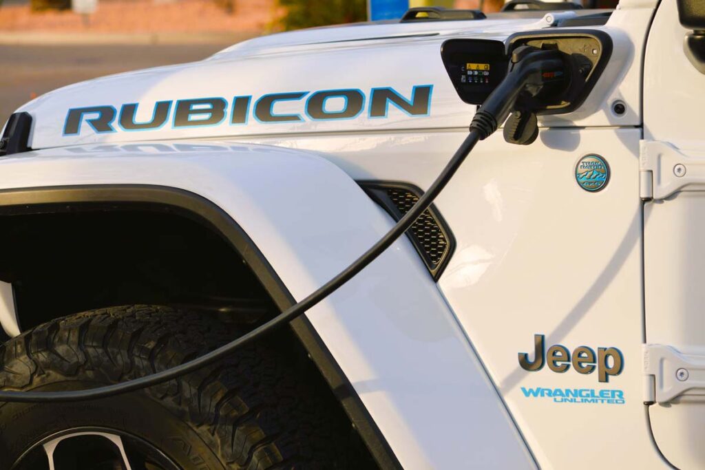 Close up of a white Jeep Wrangler 4xe plug-in hybrid plugged into a charger, representing the Jeep class action.