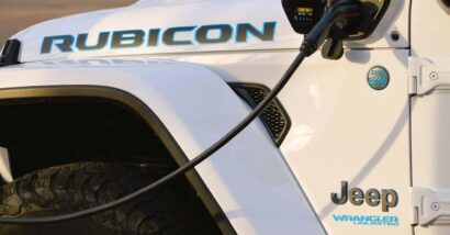 Close up of a white Jeep Wrangler 4xe plug-in hybrid plugged into a charger, representing the Jeep class action.