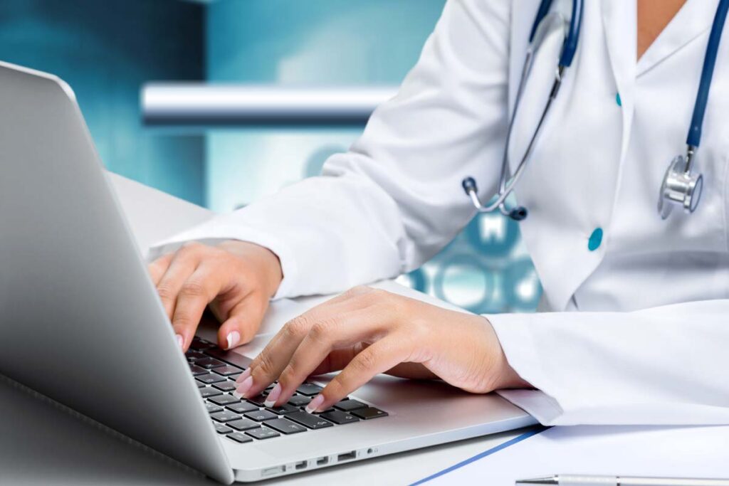 Close up of a doctor typing on a laptop, representing the Lamoille Health Partners data breach settlement.