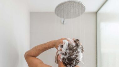 A man washing his hair with shampoo in the shower, representing Dr. Squatch shampoo class action lawsuit.