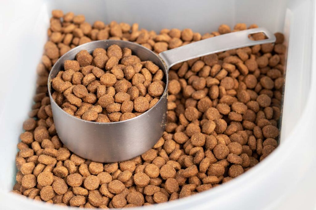 Close up of dog kibble in a container with a measuring cup, representing the Mid-America Pet Food class action.