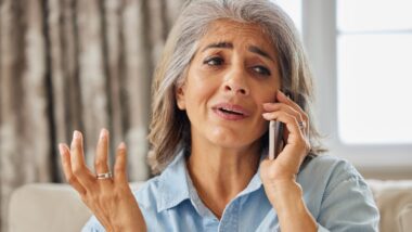 Frustrated Woman Receiving Unwanted Telephone Call At Home