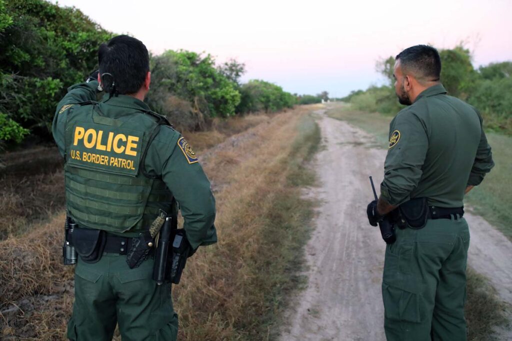 Two male border patrol agents consulting with each other, representing the Texas migrant arrest law.