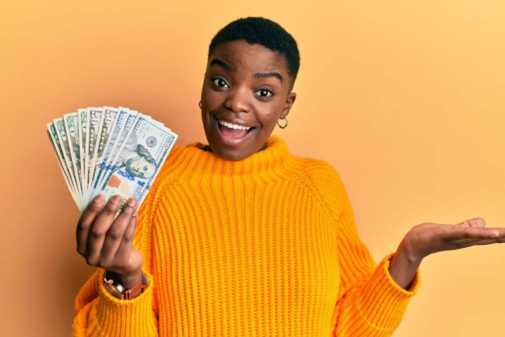 A happy woman holding cash, representing class action settlement payments.