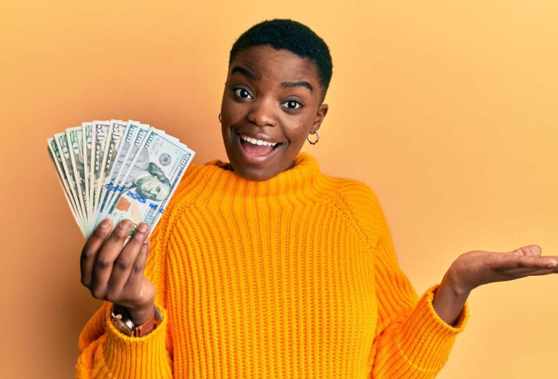 A happy woman holding cash, representing class action settlement payments.