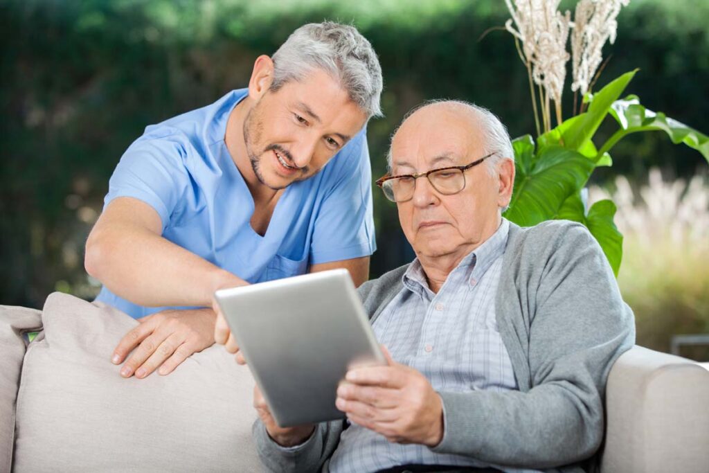A nurse and elderly man looking at a tablet on a nursing home porch, representing the ACTS Retirement Services settlement.