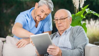 A nurse and elderly man looking at a tablet on a nursing home porch, representing the ACTS Retirement Services settlement.