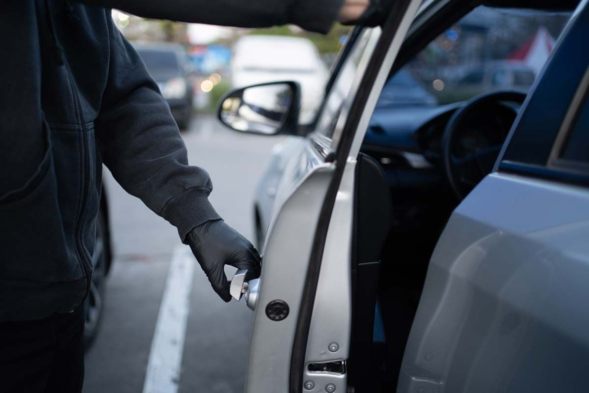 Close up of a car thief in all black opening a car door, representing Hyundai Kia car theft class action.