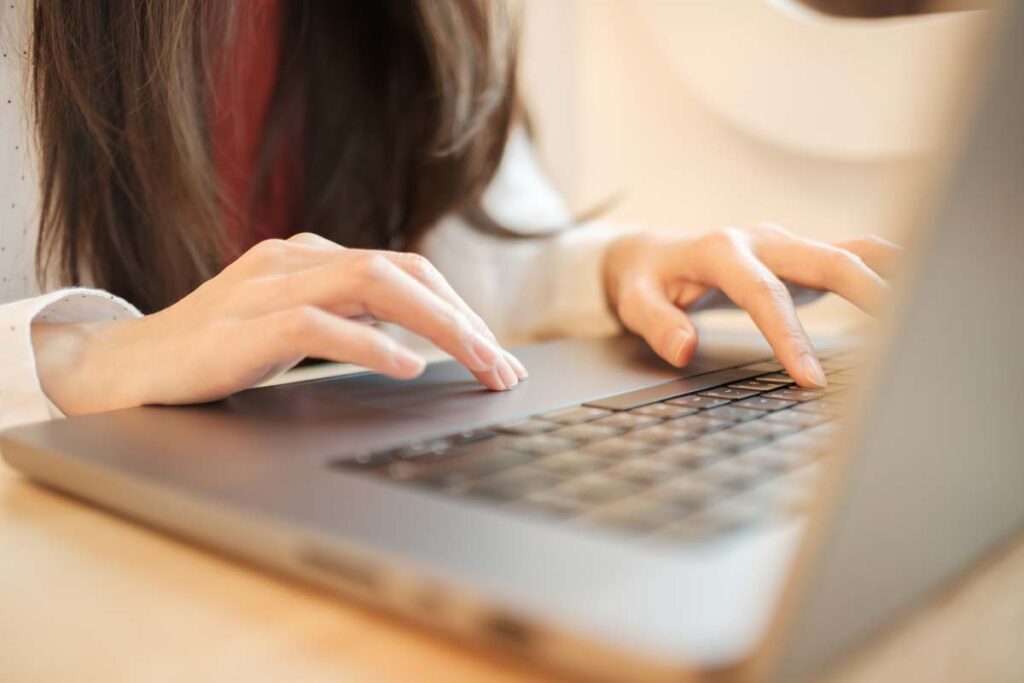Close up of a womans hands using a laptop, representing the Pillow Cube class action.
