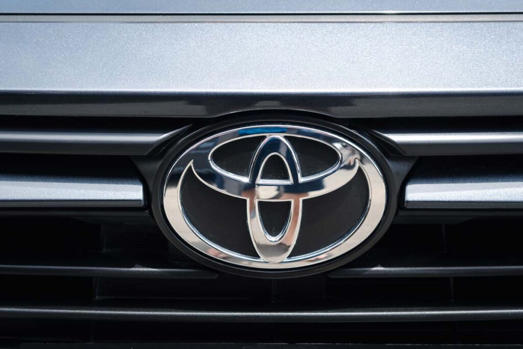 Close up of a Toyota emblem on a front bumper, representing the smelly Toyota HVAC  class action settlement.