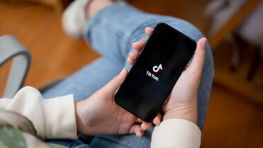 Close up of hands holding a smartphone with the TikTok logo displayed, representing the TikTok bill.