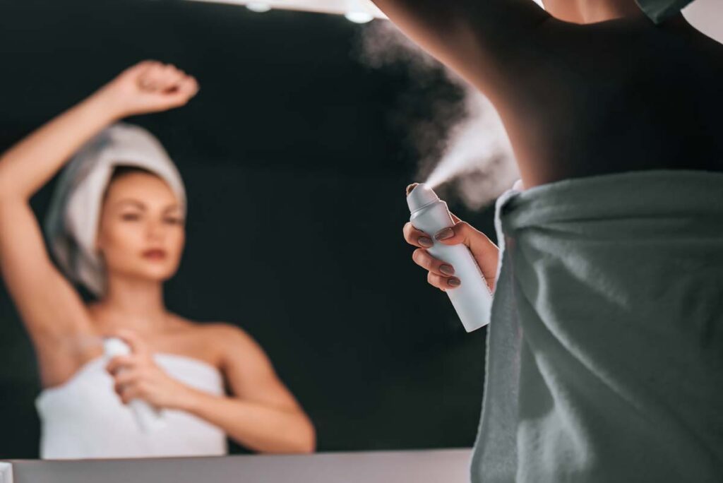 A woman using aerosol deodorant in the mirror, representing the Suave benzene settlement.