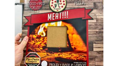 A hand holding product packaging for recalled pizza by 802 VT Frozen representing the frozen pizza recall.