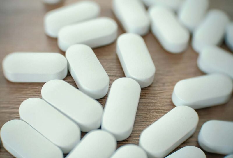 Close up of white pills on a table, representing the Amneal Pharmaceuticals opioid settlement.