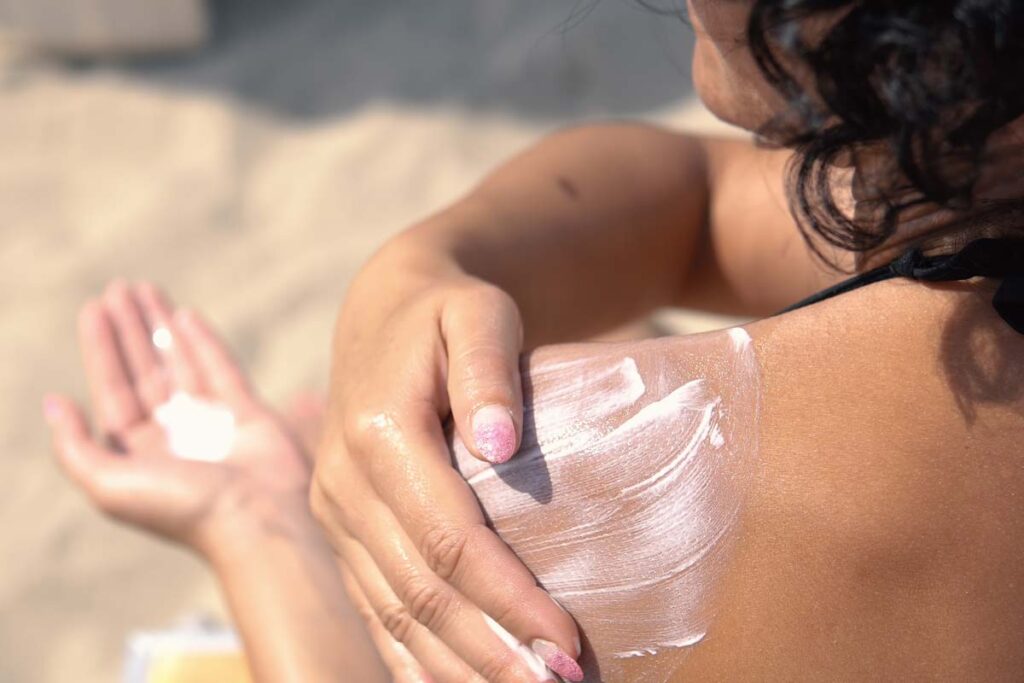 Close up of woman putting sunscreen on her shoulder, representing the sunscreen class actions.