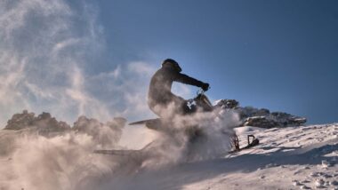 A person riding a snowmobile in a snowy landscape, representing the Arctic Cat recall.