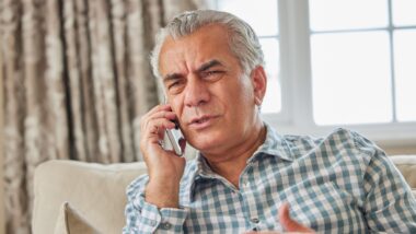 Frustrated Man Receiving Unwanted Telephone Call At Home
