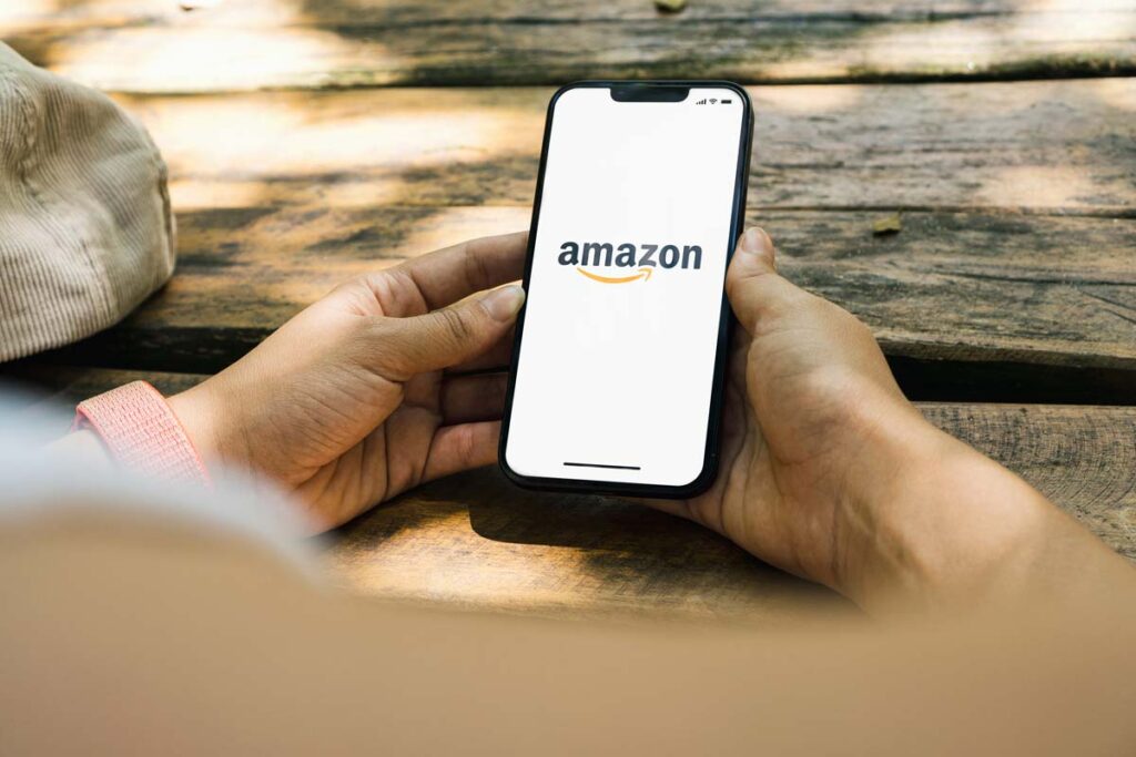 Close up of a man holding a smartphone with the Amazon logo displayed, representing the Amazon Prime cancellation lawsuits.
