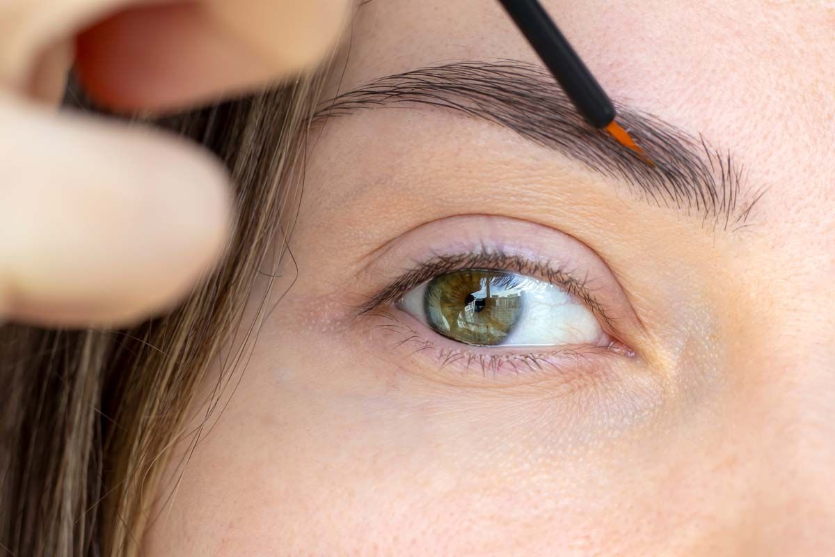 Close up of woman putting a serum on her eyebrows with a brush, representing the Babe lash and brow products.