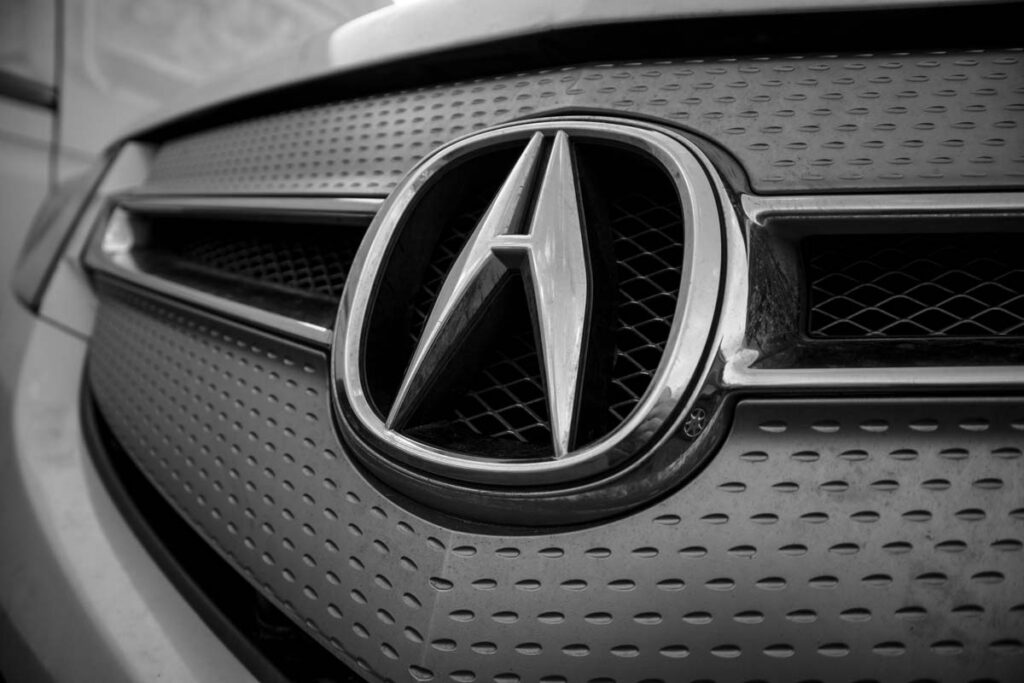 Close up of Acura emblem on a front bumper, representing the Honda hands-free defect settlement.