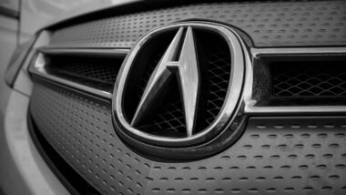 Close up of Acura emblem on a front bumper, representing the Honda hands-free defect settlement.