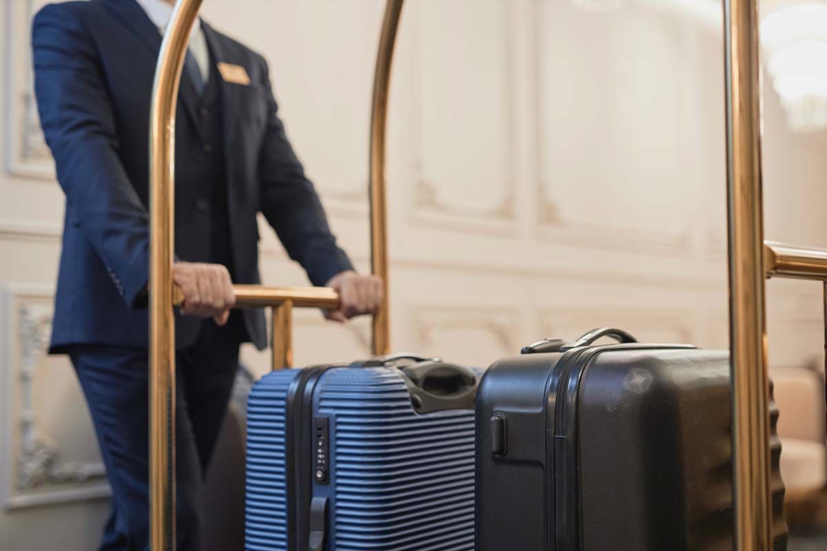 Close up of a hotel worker pushing a cart with luggage, representing the hotels price-fixing class action.