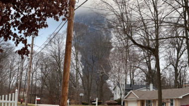 The rising smoke cloud after authorities released chemicals from a train derailment as seen from the ground in a nearby neighborhood.