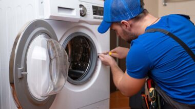 A repairman fixing a washing machine in a residential home, representing the appliance class actions.