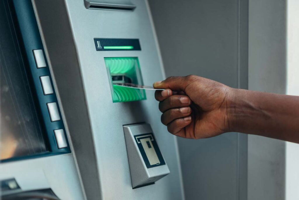 Close up of a man using an ATM, representing the Visa and Mastercard settlement.