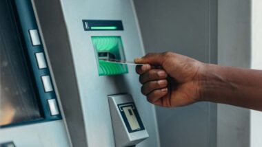 Close up of a man using an ATM, representing the Visa and Mastercard settlement.