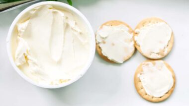 Cream cheese tub next to crackers with cream cheese, representing the cream cheese recall.