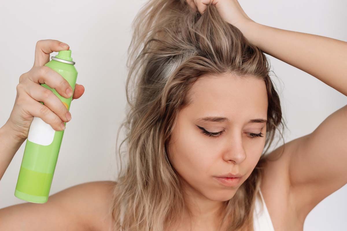 A young woman putting dry shampoo in her hair, representing the IGK dry shampoo settlement.