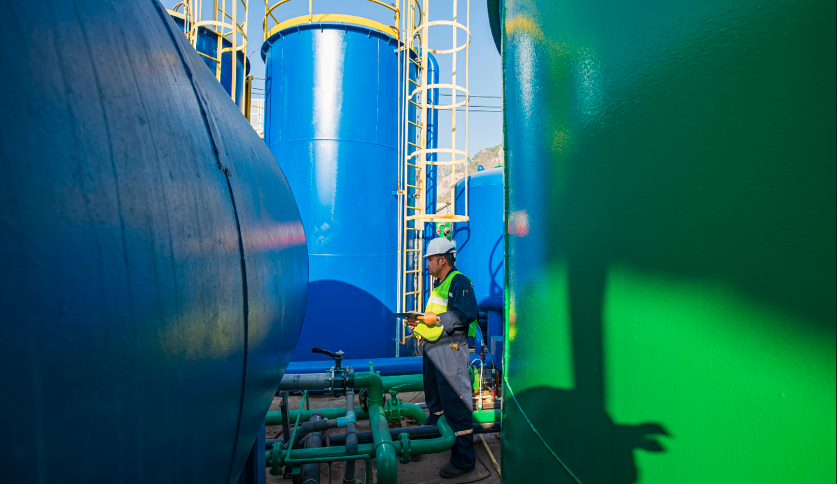 Male worker works permit industry visual inspection the row of big tanks for petrol station.