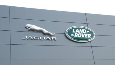 Jaguar Land Rover dealership with green oval logo on front of building with sky background.
