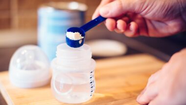 Father making baby formula in milk bottle for a newborn baby feed.