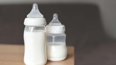 Baby bottles filled with milk sitting on a table, representing the baby bottle class actions.