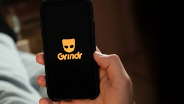 Close up of a man holding a smartphone with the Grindr logo displayed, representing the Grindr lawsuit.
