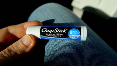 Close up of a hand holding a. Chap Stick brand product, representing the ChapStick settlement.