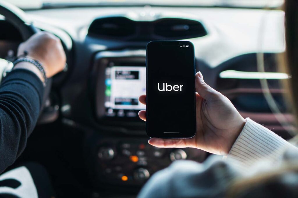 A woman using the Uber app while riding in the backseat of a car, representing Uber sexual assault MDL.